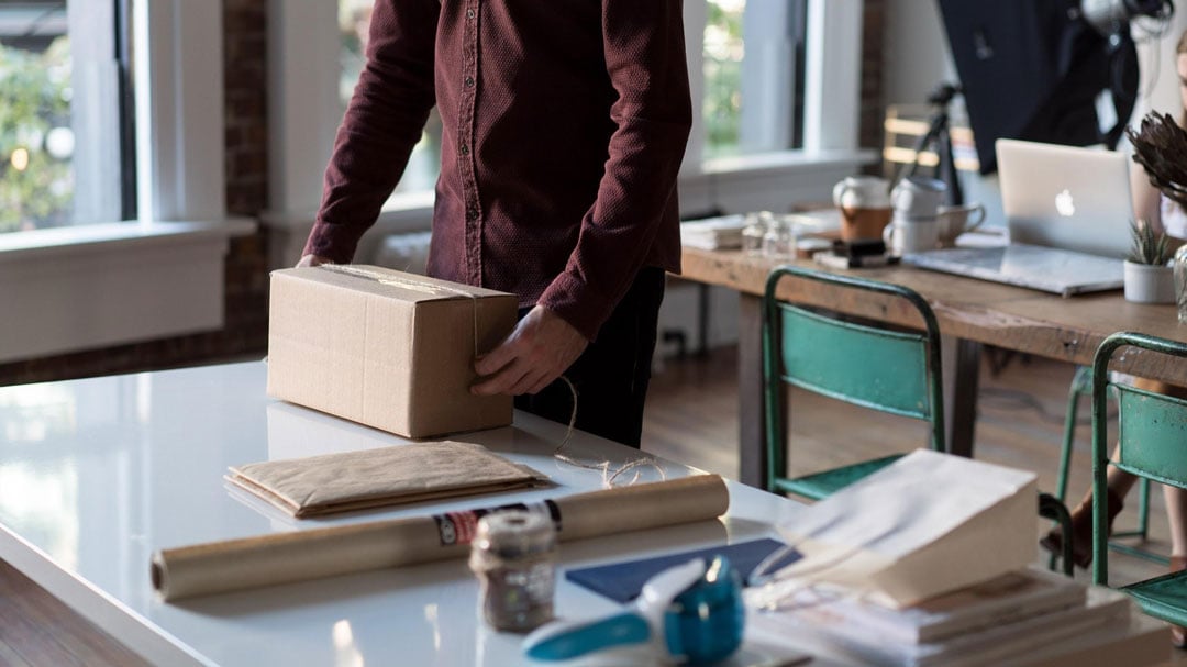 A person packaging goods to fulfill a Shopify order. 