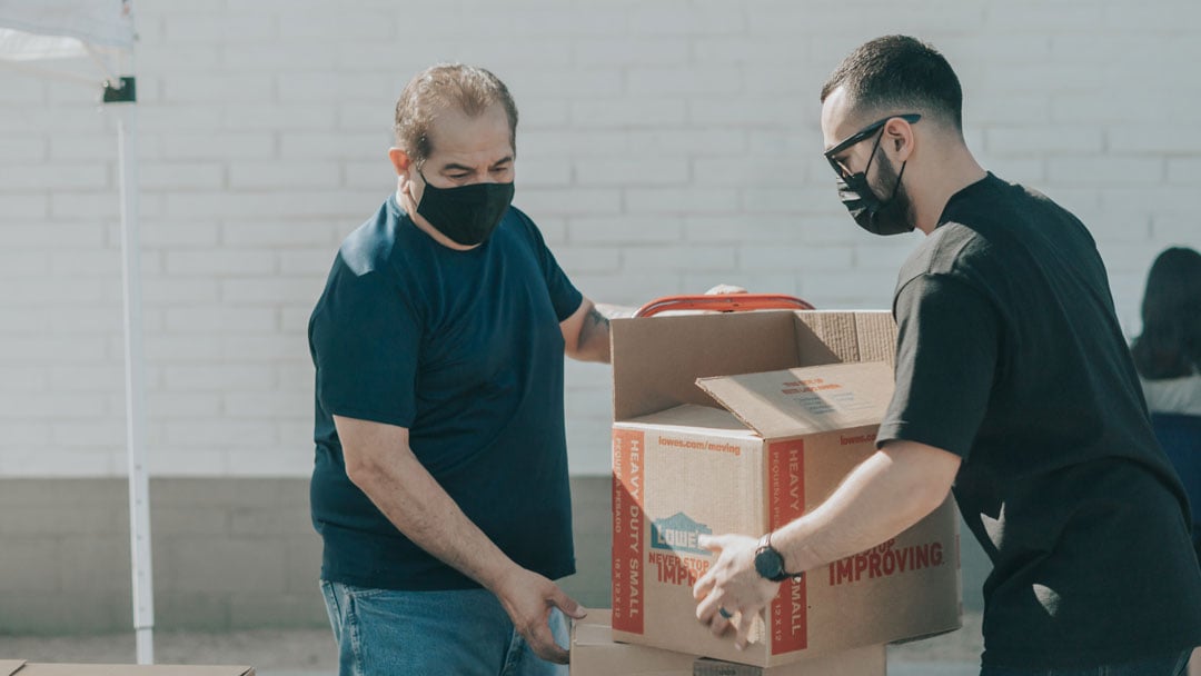 Two men in masks moving boxes for Shopify deliveries. 