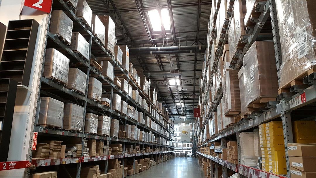 An isle of warehouse shelves full of pallets. 