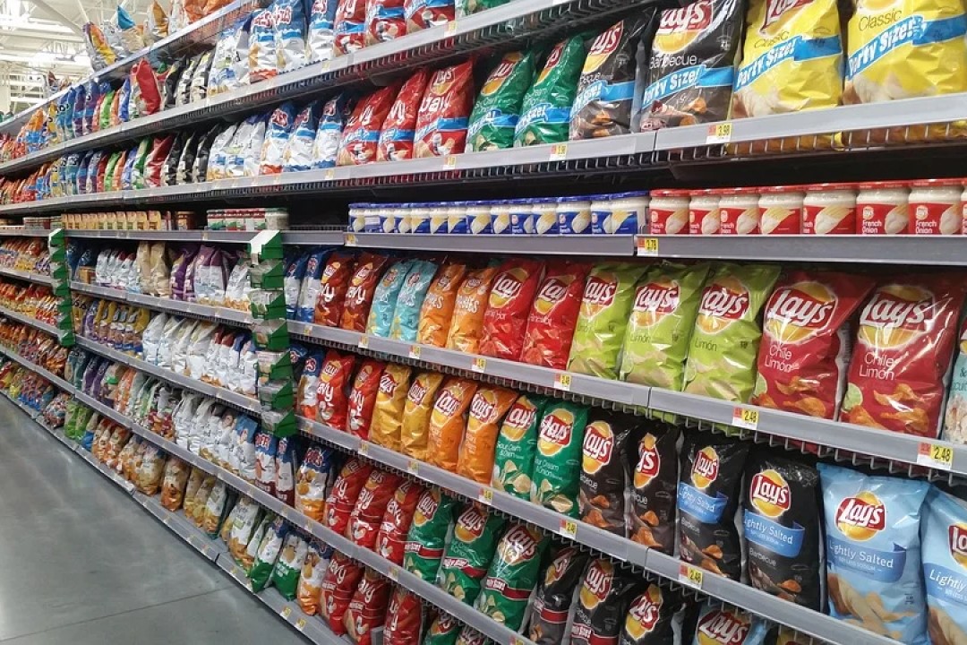 A store aisle with shelves full of packaged chips and other foodstuffs