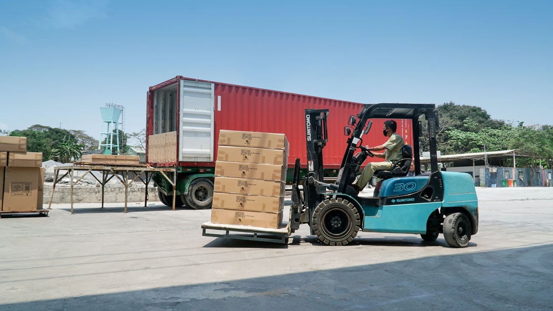 Boxes on a forklift in front of a shipping truck.